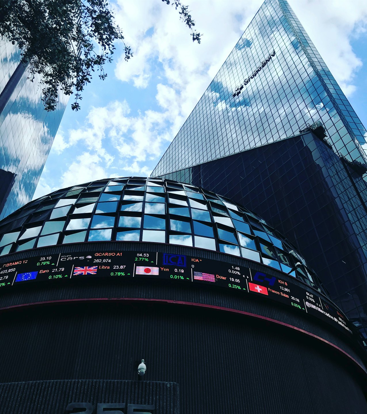 Modern financial building with digital ticker under blue sky.