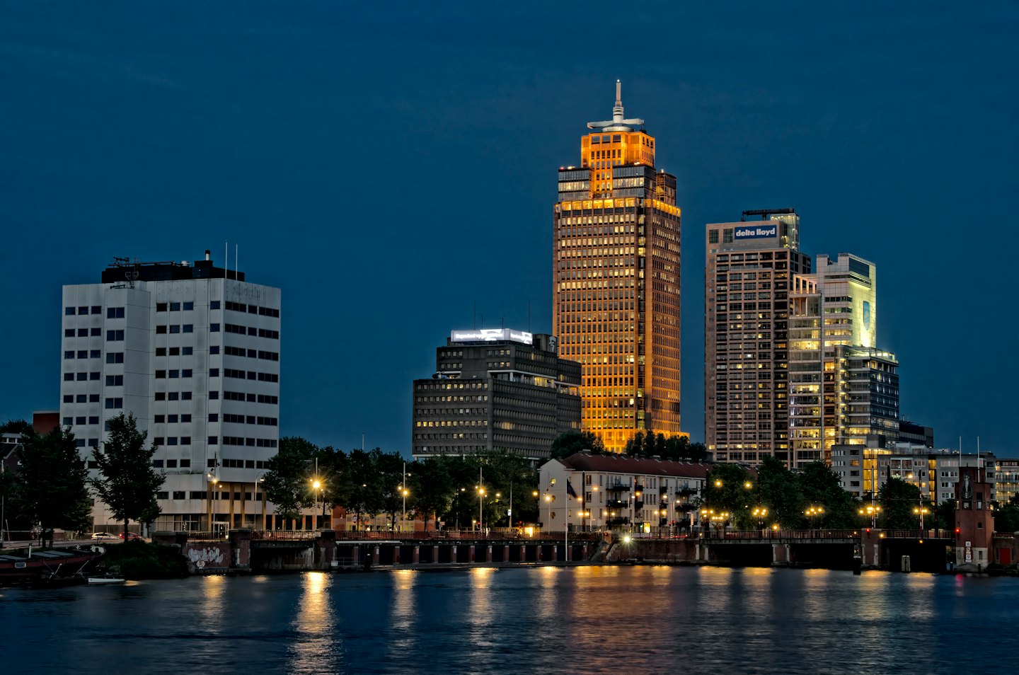 Modern city skyline reflected in the dark water at dusk.